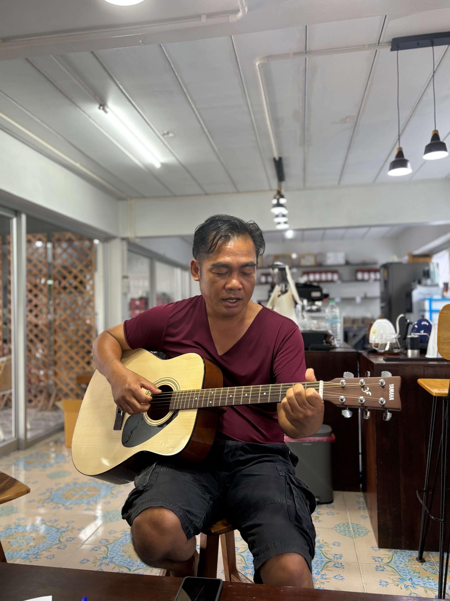 Man playing acoustic guitar in a café setting, enjoying music in a relaxed atmosphere.